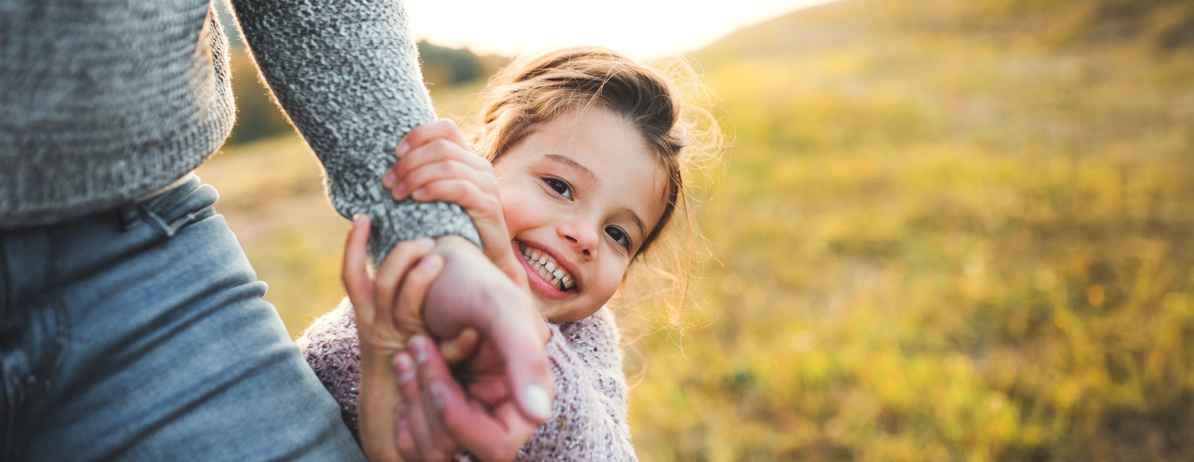 girl smiling holding parent's hand