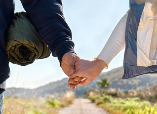 Couple holding hands while walking down a dirt road in Lyon County