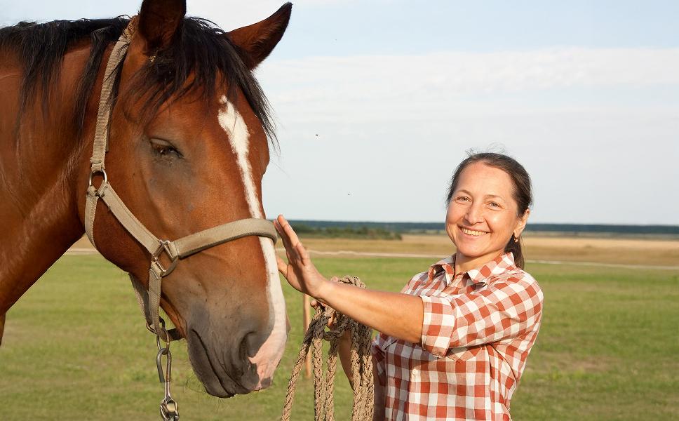 woman smiling while caring for a horse